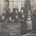 "Hommage reconnaissant aux Etats-Unis. Ecole communale (Paris) 5ème classe. Tournai." portrait en pied d'un groupe d'écoliers tenant les drapeaux des Etats-Unis et de la Belgique et de leur instituteur