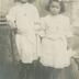 "Maria et Léonie. Yvonne te remercie infiniment de tes petits chaussons. Tante Rozine." portrait en pied de deux fillettes, Maria &amp; Léonie, en studio, devant un décor peint