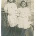 "Maria et Léonie. Yvonne te remercie infiniment de tes petits chaussons. Tante Rozine." portrait en pied de deux fillettes, Maria &amp; Léonie, en studio, devant un décor peint