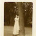 "En souvenir affectueux à ma bien chère Irma. Alice. 2/I/1915. Bâle" portrait en pied d'une jeune femme contre le tronc d'un arbre